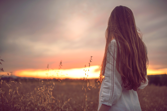 A woman looking toward a sunset horizon